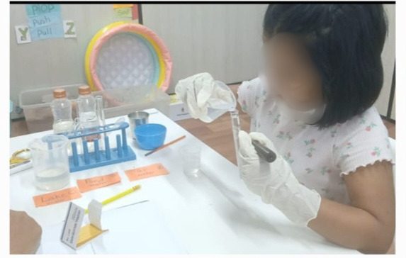 A child performing a careful lab experiment with gloves